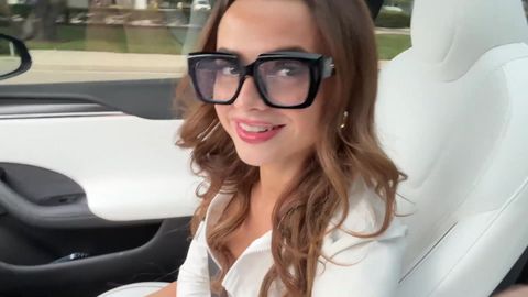 Ragazza sexy con gli occhiali scopa in una Tesla